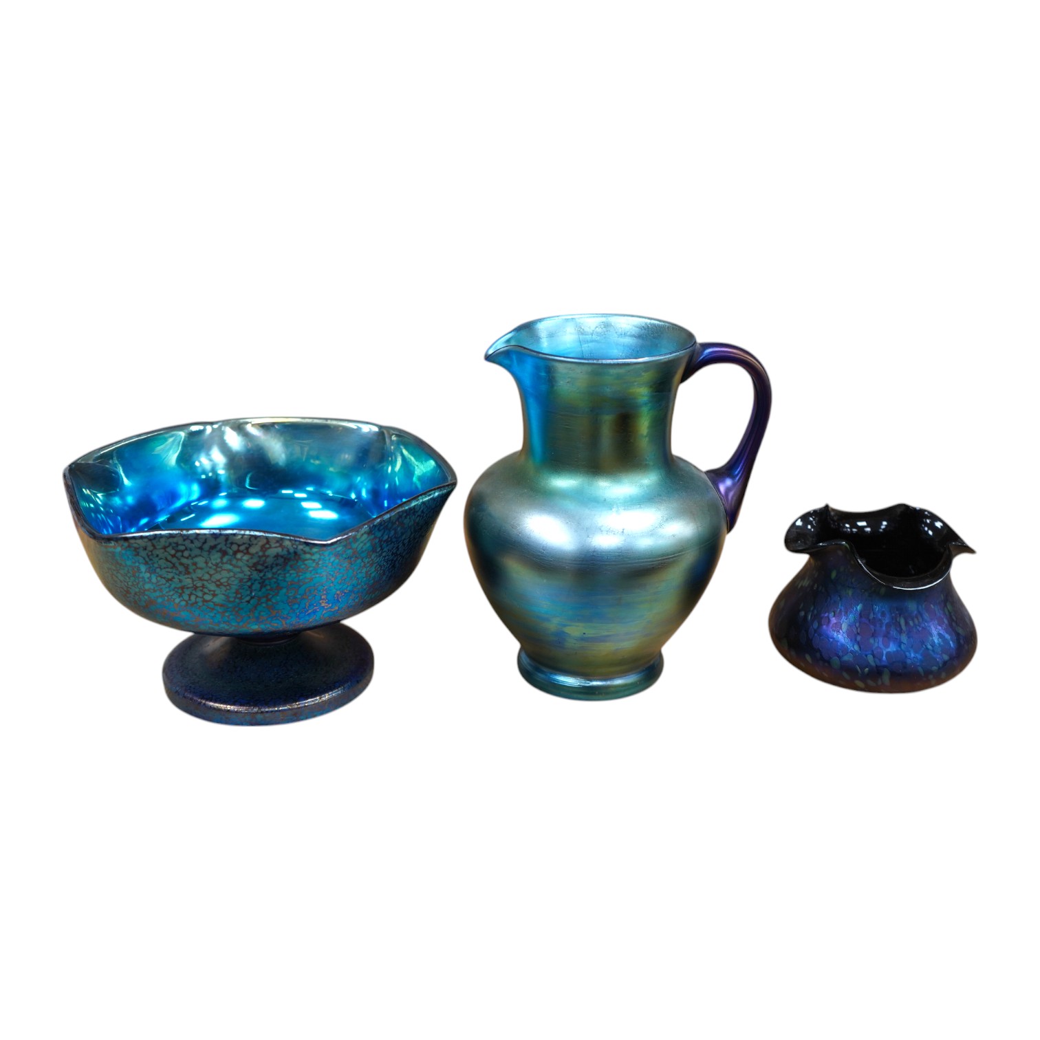 A Loetz cobalt Papillon iridescent glass footed hexagonal bowl, a Kralik blue iridescent vase and a large Bohemian iridescent glass jug (3) tallest 21cm. Condition - good